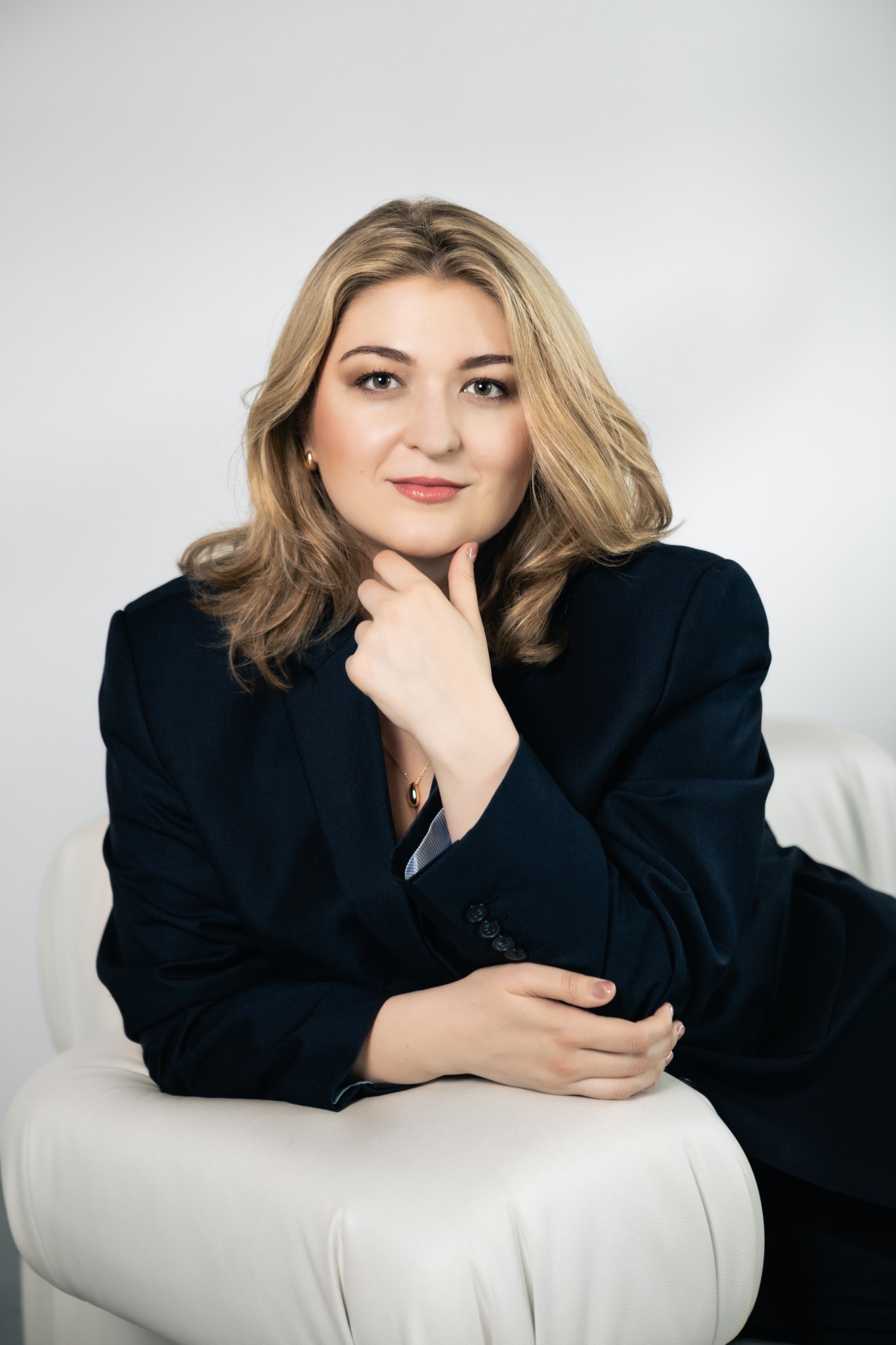 Dominika Stefańska seated in a dark suit, resting her chin on her hand