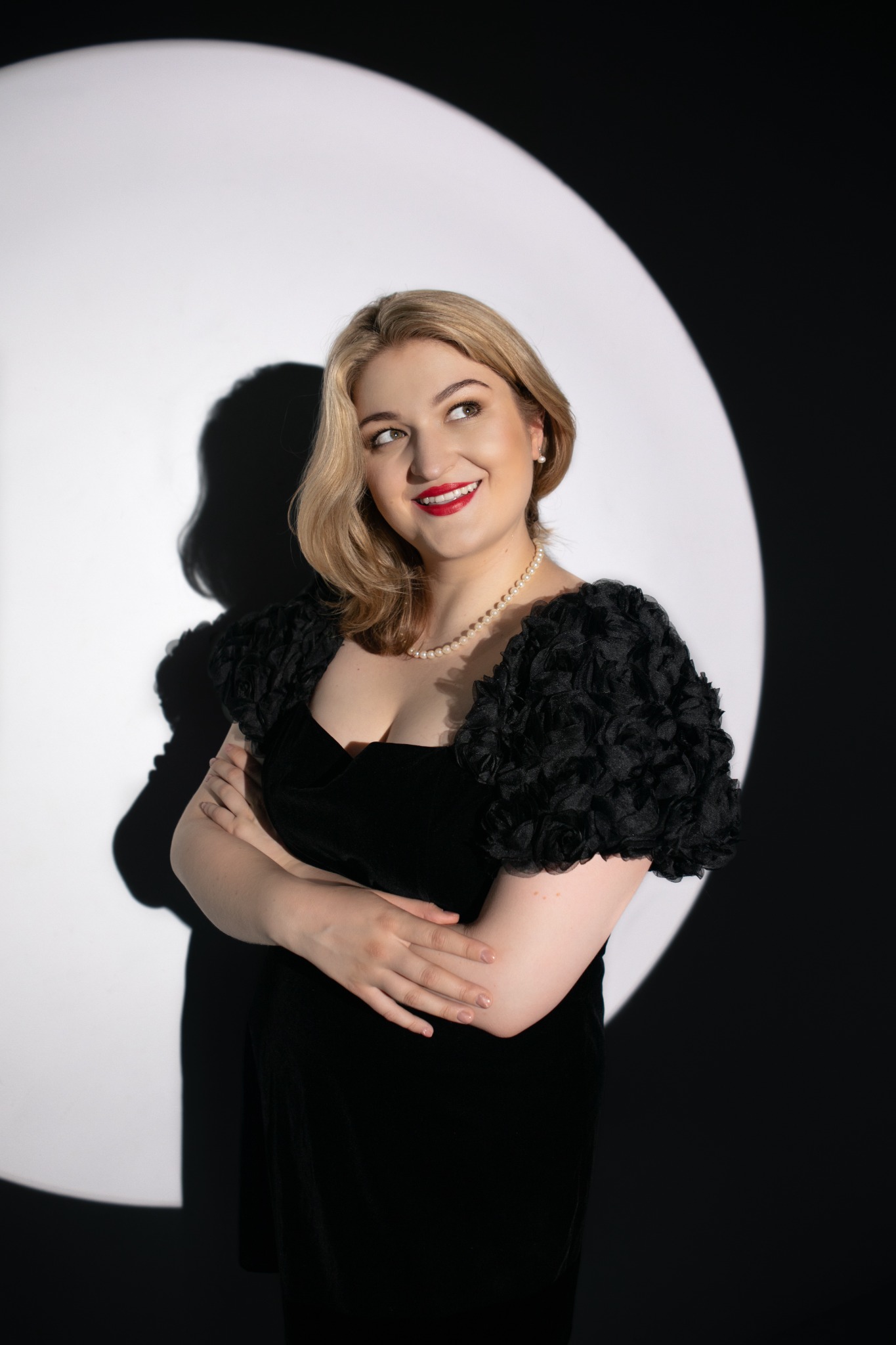 Dominika Stefańska in a black dress, standing in a circle of light